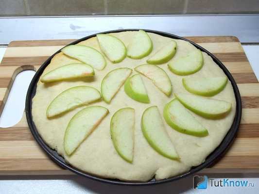 На тесто выложены яблоки