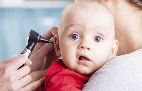 Ребенку с опущенным углом рта осматривают ухо