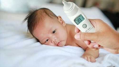 Младенец лежит в постели с высокой температурой