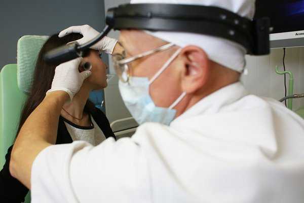 Женщина-врач осматривает ухо маленькому ребенку