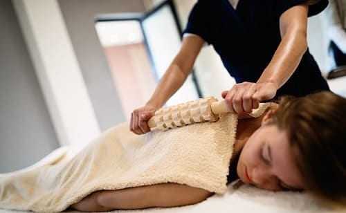 Женщине делают массаж роликом