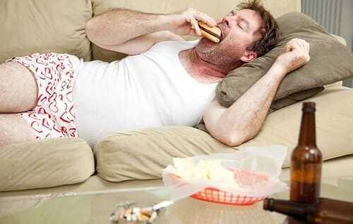 Мужчина пьет, курит, ест гамбургер