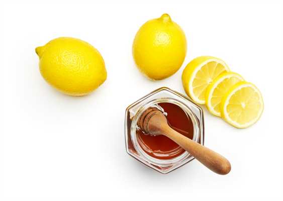 Открытая баночка меда с ложкой и лимоны