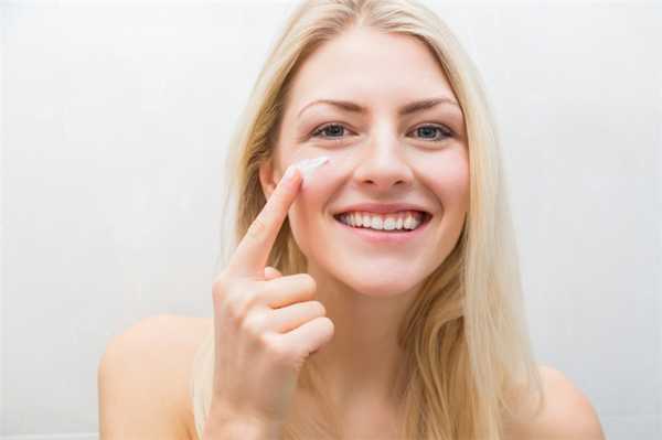 Девушка наносит на сухую кожу лица крем