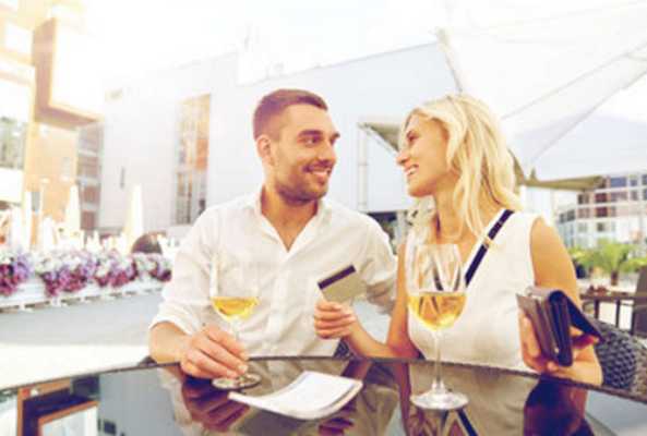 Мужчина с женщиной сидят в кафе с бокалами вина. Женщина достала из сумочки кредитку