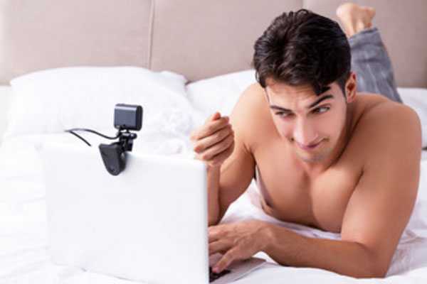 Альфонс лежит на постели перед ноутбуком с камерой